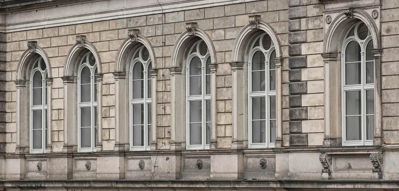 Fachada clásica con ventanas de madera blancas en arcos de medio punto